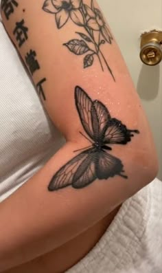 a woman's arm with a butterfly tattoo on it and chinese writing in the background