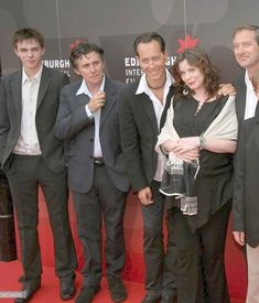 a group of people standing next to each other on a red carpet