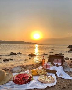 a picnic on the beach with watermelon, cheeses and wine at sunset