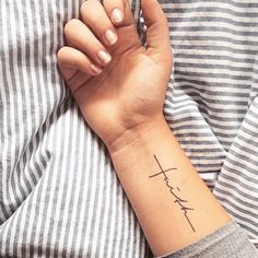 a woman's wrist tattoo with the word faith on her left hand and a cross in the middle