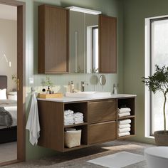 a bathroom with green walls and white towels on the counter top, along with wooden cabinets