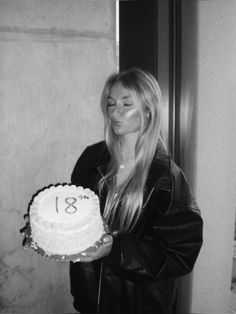 a woman holding a cake with the number thirteen on it in front of her face