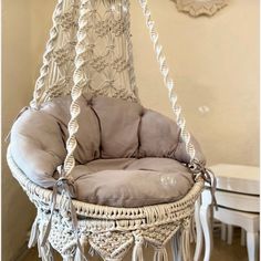 a white wicker hanging chair with grey cushions