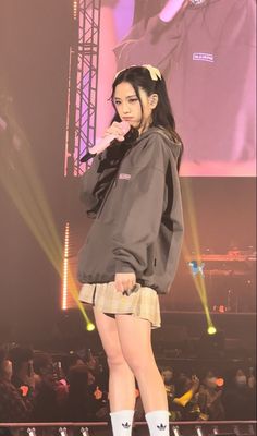 a woman standing on top of a stage wearing short shorts and a hoodie jacket