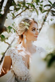 a woman in a wedding dress standing under a tree with white flowers on her head