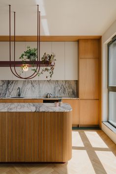 a kitchen with marble counter tops and wooden cabinets, hanging planters on the wall