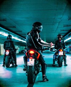 three people riding motorcycles in an underground parking garage with lights on and one person sitting on the motorcycle