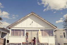 two women standing on the porch of a house with surfboards in front of them