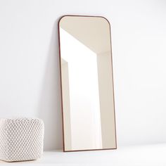 a large mirror sitting on top of a white counter next to a vase and potted plant