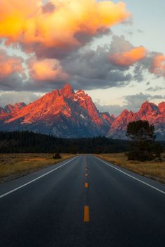 an empty road with mountains in the background