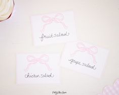 three place cards with pink bows on them