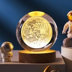 an astronaut's moon lamp on top of a wooden base