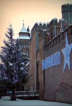 a large brick building with a christmas tree in the foreground and lights on it