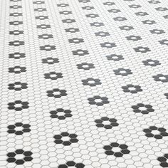 a white tiled floor with black circles and dots on it's surface, in the shape of hexagonal tiles