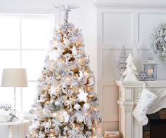 a white christmas tree with snowflakes on it in front of a fire place