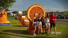 some people are standing in front of an orange sculpture