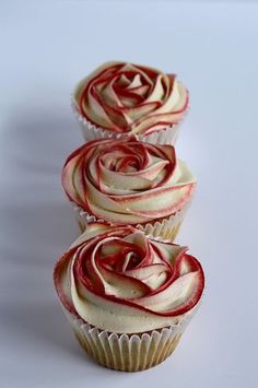 three cupcakes with red and white frosting on them sitting side by side