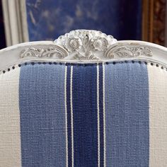 an upholstered blue and white striped chair with silver details on the armrests