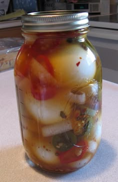 a jar full of pickles sitting on top of a table next to a counter