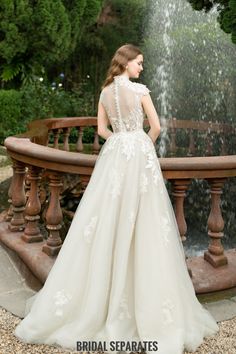 a woman standing in front of a fountain wearing a wedding dress