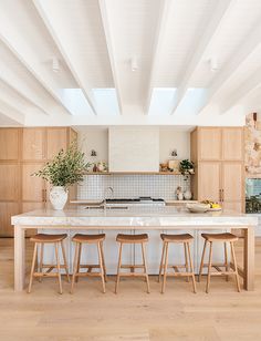 a large kitchen with wooden cabinets and white counter tops, along with two stools