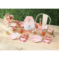 the table is set with pink and white plates, napkins, wine bottles, and flowers