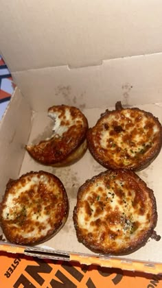 four small pizzas in a box with cheese toppings on the top and bottom