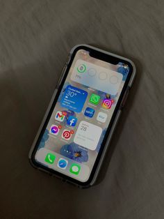 an iphone is sitting on a bed with the cover pulled back to reveal its home screen