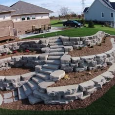 a stone wall with steps leading up to it in front of a house and lawn