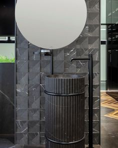 a round mirror on the side of a wall next to a trash can in a bathroom