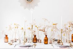 a white table topped with lots of vases filled with flowers and candles on top of it