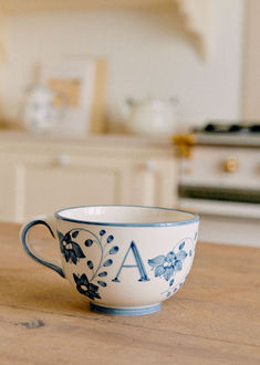 a blue and white coffee cup sitting on top of a wooden table in a kitchen