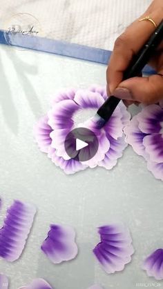 someone is painting purple flowers on a sheet of paper