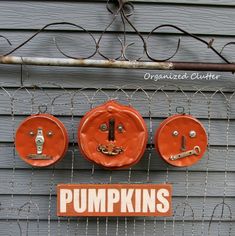 there are four pumpkins hanging on the wall next to a sign that says pumpkins