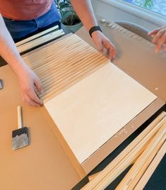 a person working on some kind of crafting project with wood sticks and pliers