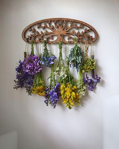 a bunch of flowers are hanging from a wooden wall hanger on a white wall