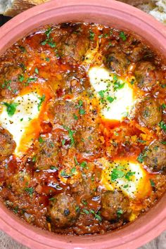 meatball soup in a red bowl with bread on the side and garnished with parsley