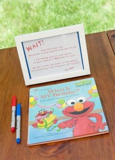 the sesame street book is next to a marker and pen on a wooden table with a sign that says, i want my birthday