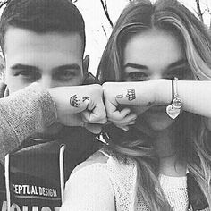 two people are holding their hands together with tattoos on their fingers and pointing at the camera