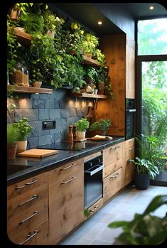 a kitchen filled with lots of green plants and wooden cabinets next to a large window