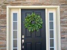 a black front door with a green wreath on it