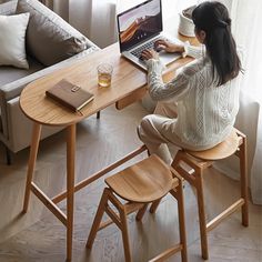 a woman sitting at a table with a laptop computer on her lap and looking out the window