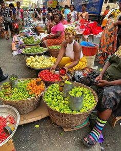 several people sitting around baskets of fruit and vegetables