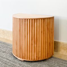 a round wooden table sitting on top of a carpeted floor next to a wall