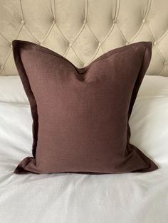 a brown pillow sitting on top of a white bed