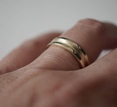 a person's hand with two gold wedding bands on their fingers, one ring is slightly bent to the side