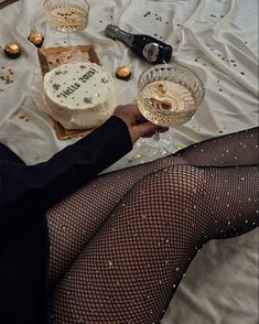 a woman in fishnet stockings holding a wine glass with a birthday cake on it