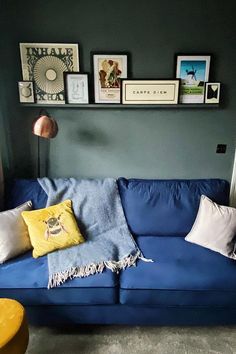 a blue couch with pillows and pictures on the wall