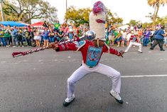 a man in a red and white uniform holding a baseball bat while standing on the street