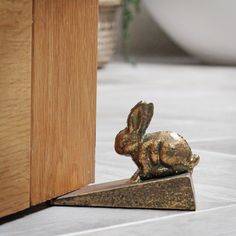 a small gold rabbit statue sitting on top of a wooden floor next to a door